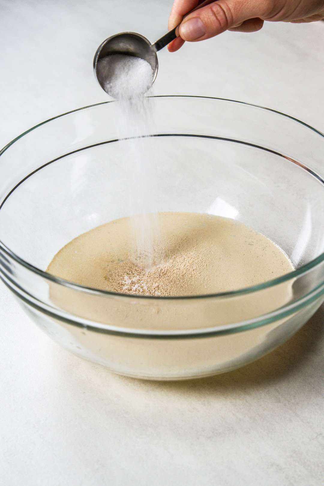 Pouring sugar into a bowl with yeast