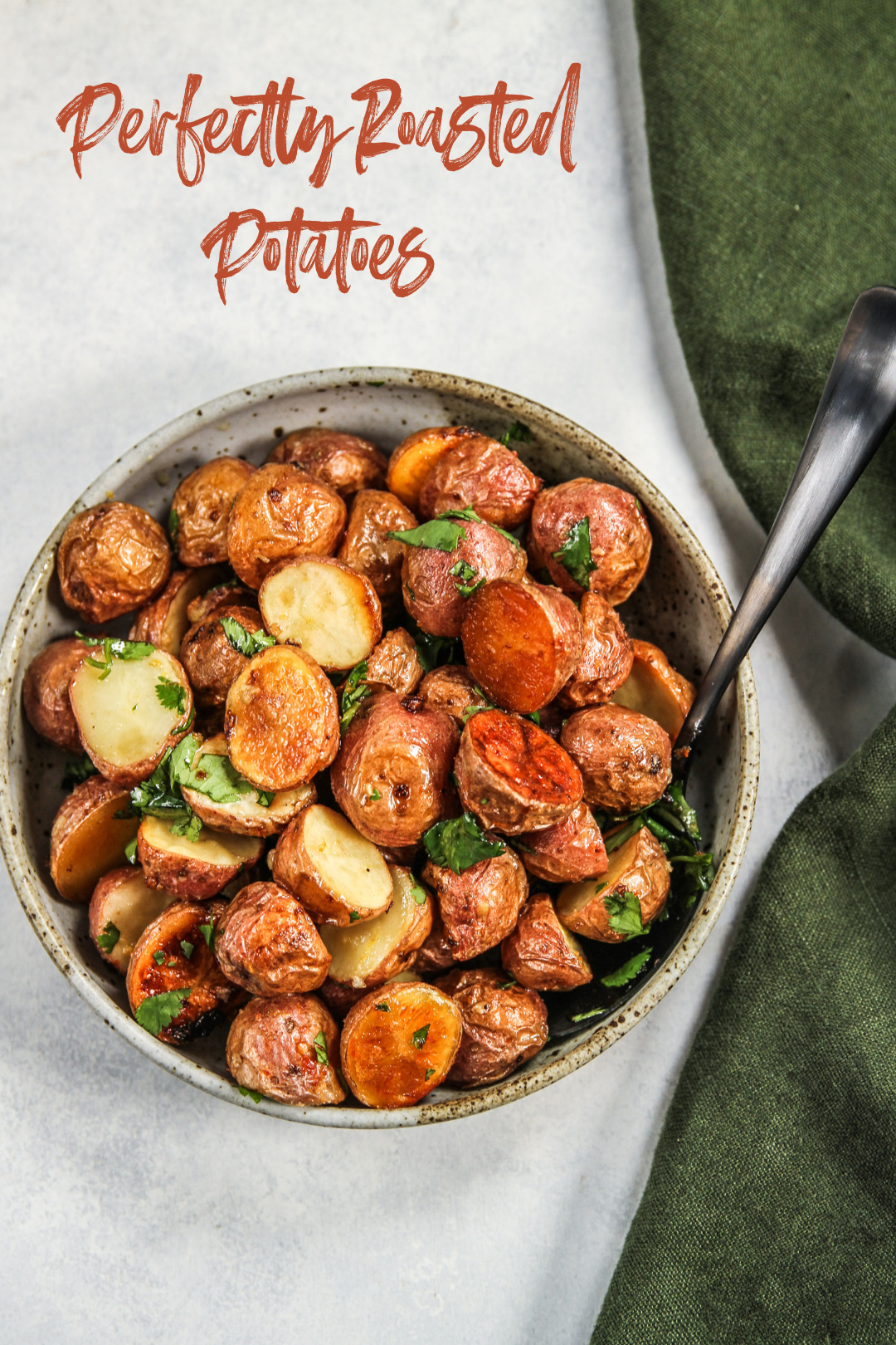 Perfectly roasted potatoes in a shallow bowl with green napkin