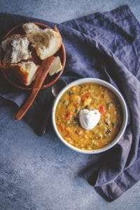 Lentil and vegetable soup with sour cream in white bowl