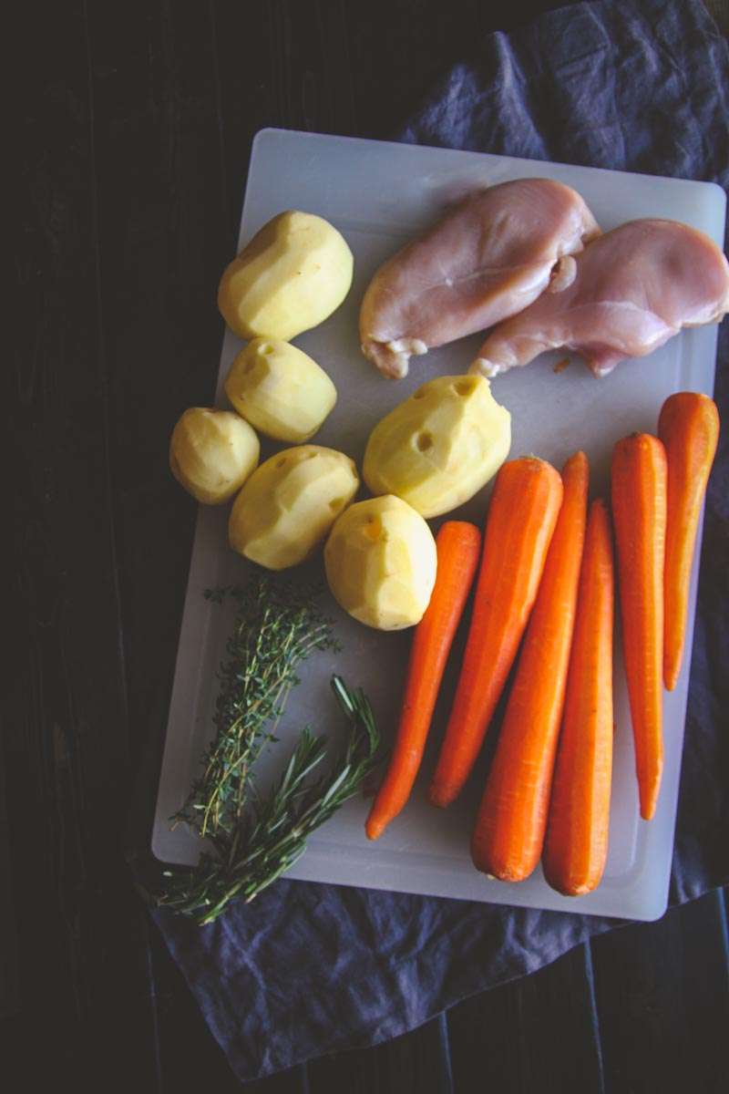 Ingredients for baked chicken, potatoes carrots and herbs