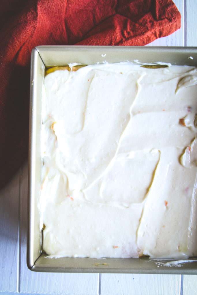 Layer of cheesecake in carrot cake coffee cake in a baking dish