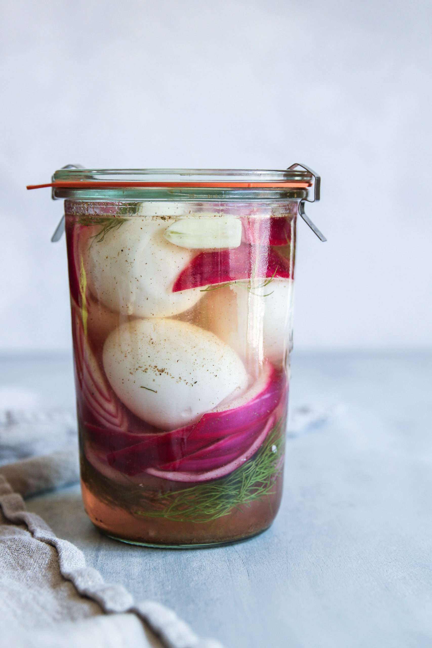 Pickled eggs with red onion slices in a Weck jar
