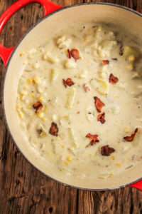 Creamy soup with bacon in a red pan
