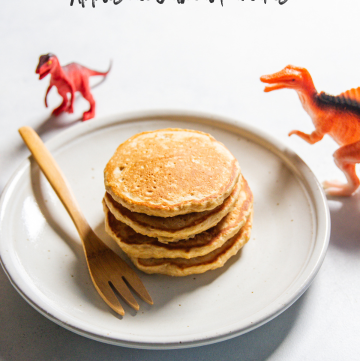 Applesauce oatmeal pancakes on white plates with toy dinosaurs